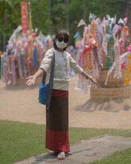 Asian tourist female people wearing Northern Thai dresses traditionally donations of beautiful colored paper flags and offer to on the sand pagoda at temple.