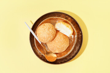 Plate with delicious choux pastry on yellow background