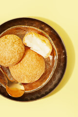 Plate with delicious choux pastry on yellow background