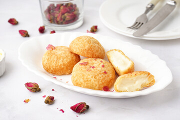 Plate with tasty choux dessert on light background