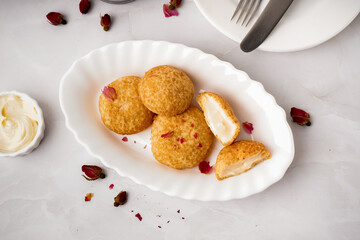 Plate with tasty choux dessert on light background