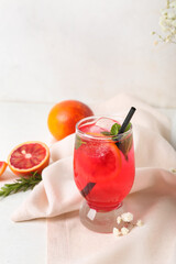 Glass of tasty blood orange lemonade on light background