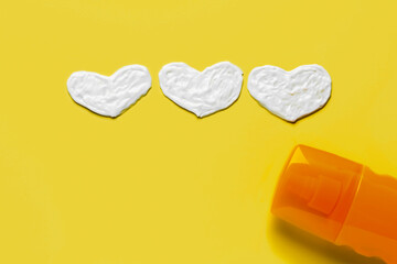 Hearts made of sunscreen cream on yellow background