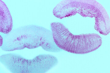 Purple lipstick kiss marks on blue background, closeup