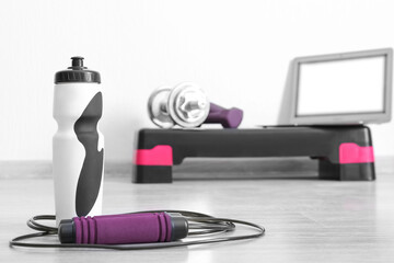 Sports water bottle with skipping rope in gym, closeup