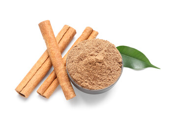 Bowl of powder with cinnamon sticks and leaf on white background