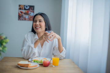 Obraz na płótnie Canvas Beautiful asian girl sitting and joyful with her breakfast with smile on her face.