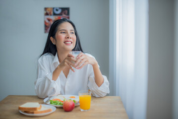 Obraz na płótnie Canvas Beautiful asian girl joy with her breakfast while looking to the copy space with smile on her face.