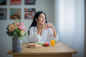Obraz na płótnie Canvas Beautiful asian girl looked content and relaxed as she savored the flavors of her breakfast meal.