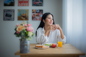 Obraz na płótnie Canvas Beautiful asian girl happiness with her breakfast while looking to window with smile on her face