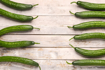 Frame made of cucumbers on light wooden background