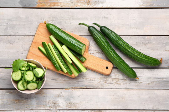 Bowl with fresh cut cucumber on light wooden background
