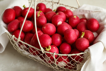 Basket with fresh radish on light background