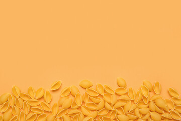 Heap of raw conchiglie pasta on yellow background