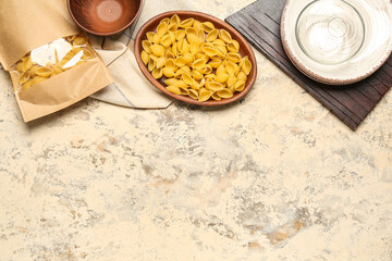 Bowl with raw conchiglie pasta on grunge background
