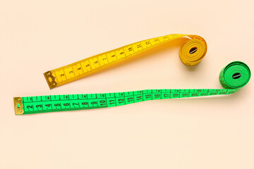 Orange and green measuring tapes on beige background