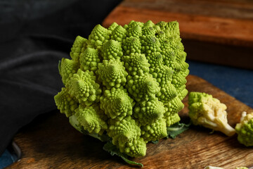 Wooden board with romanesco cabbage on blue grunge table