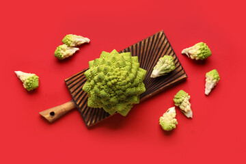 Composition with romanesco cabbage and wooden board on red background