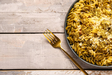 Plate of tasty Italian pasta with Parmesan cheese on light wooden background, closeup