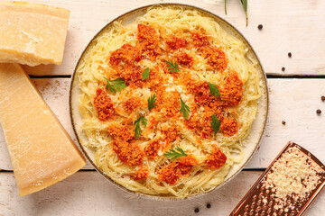 Plate of tasty Italian pasta with Parmesan cheese on light wooden background