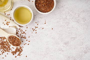 Bowl with flax oil and seeds on light grunge background