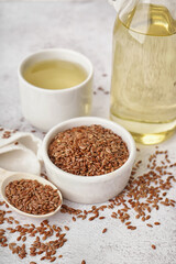 Bowl and spoon with flax seeds on light grunge background