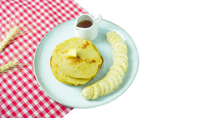 Pancake with banana and chocolate source on a white plate and red check tabke cloth. 