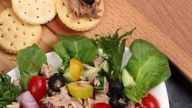 Use of can tuna fish chunk flake product recipes salad spread topping tapas cracker sandwich patty burger kebab on wooden black slate board over rustic wooden table pan move rotate zoom out