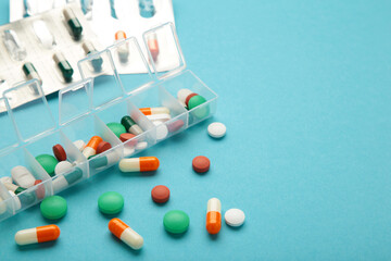 Daily pill box with medications and nutritional supplements on blue background. Space for text