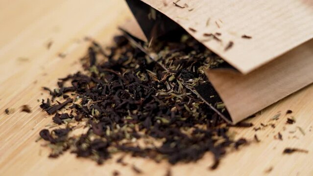 Scattering packaged black herbal tea with thyme in paper pack close up. Rotation. Slow motion