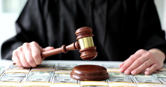 Judge knocks wooden gavel on dollar bills closeup. Financial fraud and litigation
