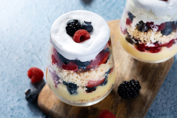 Trifle dessert with berries and cream on blue background