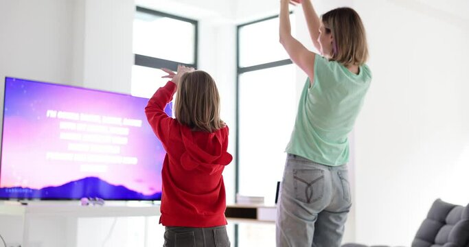 Active family dancing with modern game console at home. Mom and daughter dancing in front of tv
