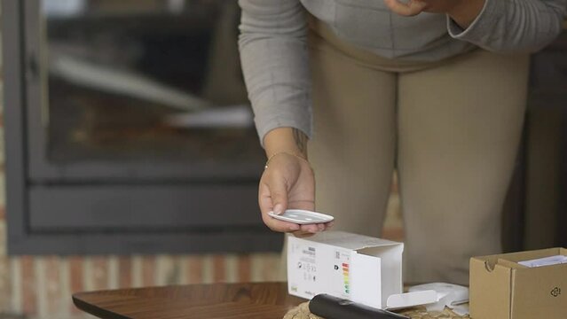Woman installing a magnetic control of the led light she bought, in the living room.