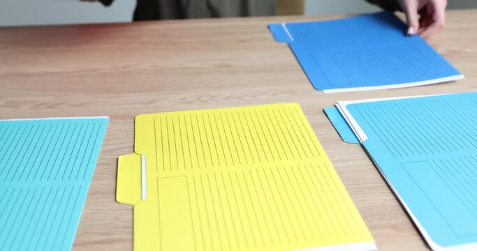 Secretary manager lays out colored folders on table. Preparation of business documentation