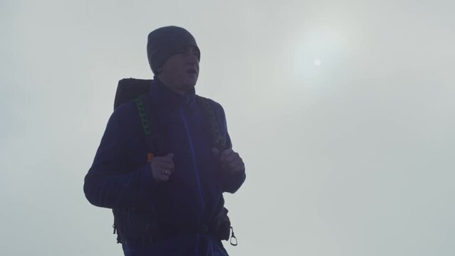 A man with a makes his way through the fog, bad weather, on a hike. A tourist walks in the mountains among the clouds. A guy is looking for a way out during bad weather, when nothing can be seen. 4k