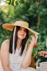 Beautiful woman with dark hair brunette wearing summer hat on vacation in the park garden portrait