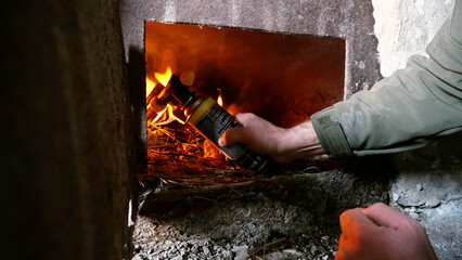 The guy lights a fire in the oven. To lay firewood. An old stove in an abandoned hut. Rusty metal...