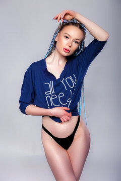 Young beautiful female with long pigtails hairstyle wearing oversize t-shirt and black panties posing against gray background. Studio shot copy space
