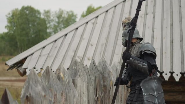 Dark knight sneaks into settlement to fight village residents. Evil warrior prepares to attack local people. Medieval battles closeup on blurred background