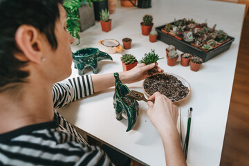 Young woman planting a succulent in a flower pot