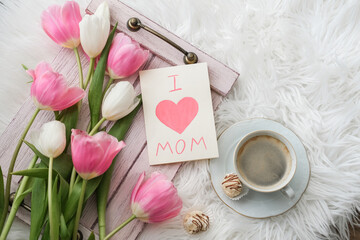 A bouquet of tulips, a cup of coffee and a card with the text I love mom on a tray. Mother's day concept