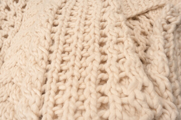 A fragment of beige knitted fabric, knitted from white sheep wool.
