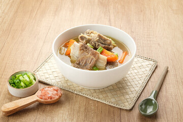 Sop Iga (Beef ribs soup) made from ribs, carrots, leeks.  Served in white bowl. Indonesian food
