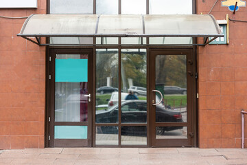 The front door of a office block, reflecting buildings in the glass