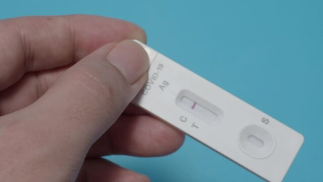 POV of Man hands using Rapid antigen test kit or ATK and blue background. Covid 19 rapid antibodies test kit for detecting antibodies and immunity in 15 minutes. Easy Coronavirus protective check up.