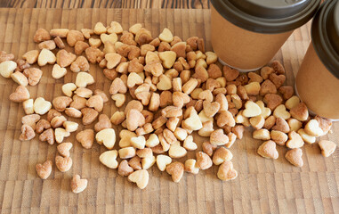 Cookie hearts and two disposable coffee cups. The concept is a romantic date.