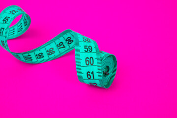 Blue tape measure on pink paper background diet concept
