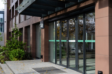 The front door of a office block, reflecting buildings in the glass