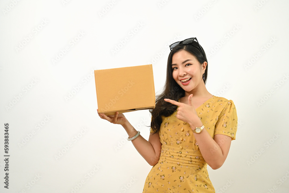 Wall mural happy asian woman holding cardboard box isolated on white background. delivery, unpacking and shippi